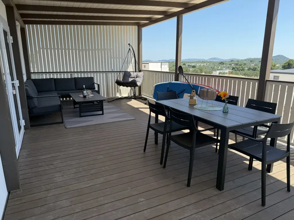 Covered terrace with lounge seating, dining table and SUP board